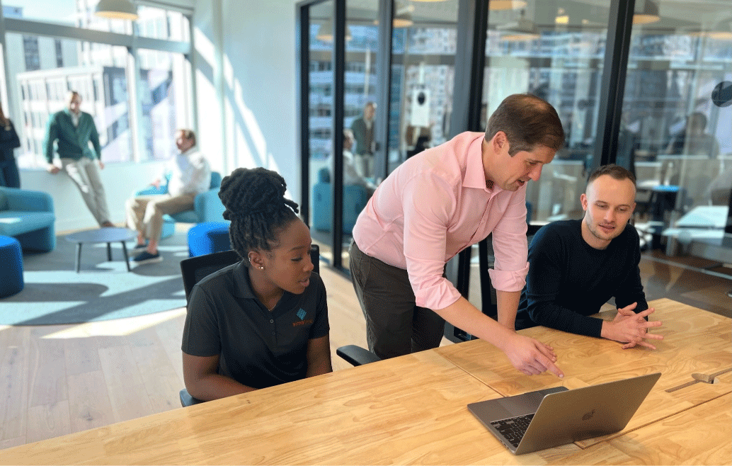 Patrick, Kit, and another person looking at laptpo on table